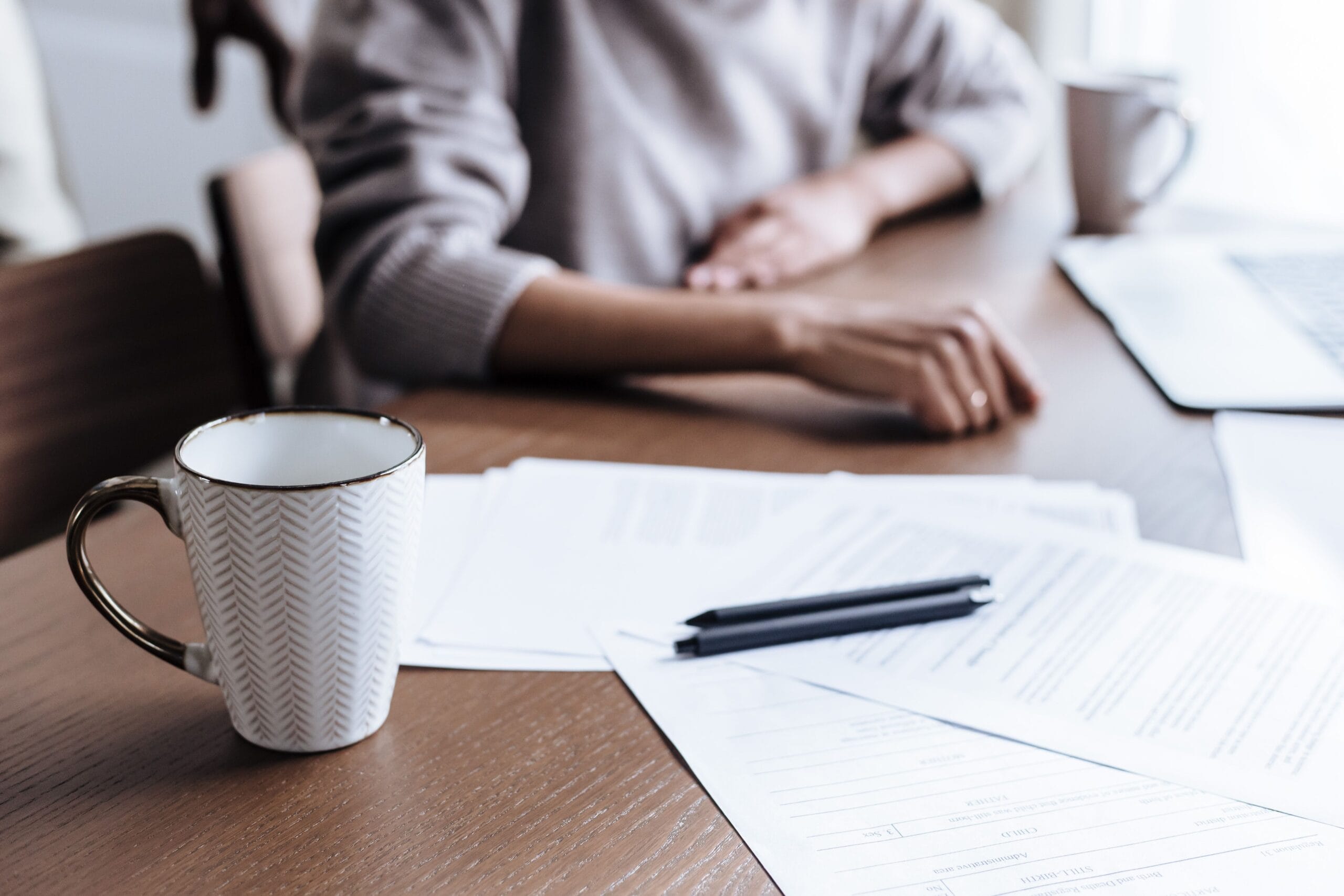 A laptop and paperwork on a desk, the setup needed to request a Spanish digital certificate online before accrediting your identity in person